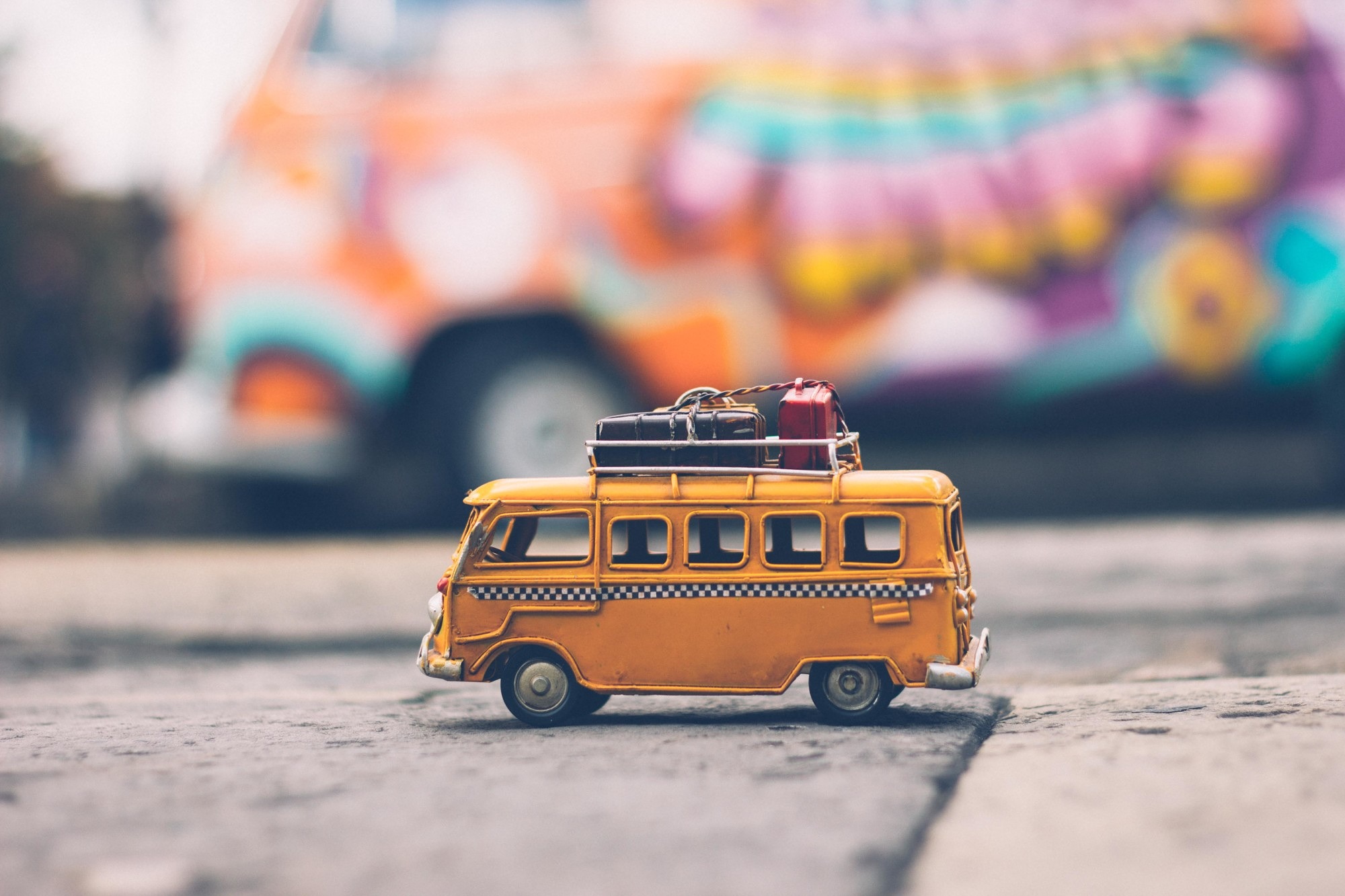 gelber Spielzeug-Bus mit Koffern auf dem Dach