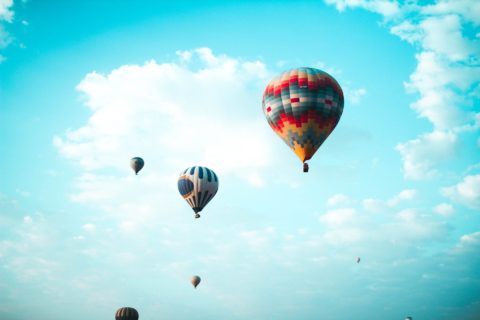 Foto von schwebenden bunten Heißluftballons vor türkisblauem Himmel mit weißen Wolken