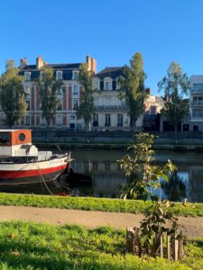 Foto eines Stadtkanals mit Bötchen, dahinter eine Reihe alter französischer Wohnhäuser, Rennes, Frankreich